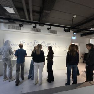 Schüler schauen sich in einer Ausstellung eine Abbildung an.